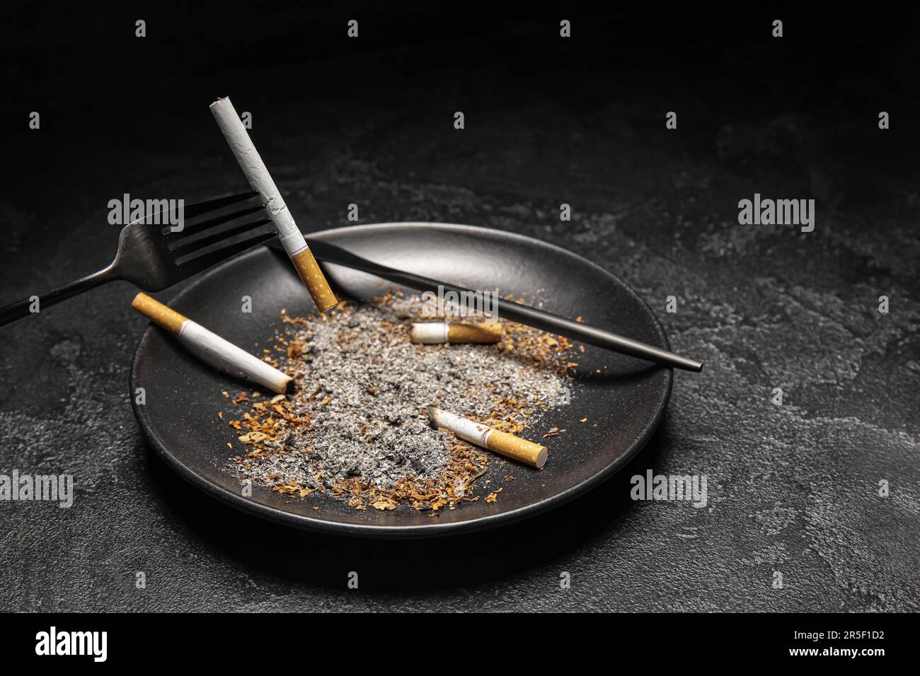 Plate with cigarettes, ash and cutlery on dark background. Stop smoking  concept Stock Photo