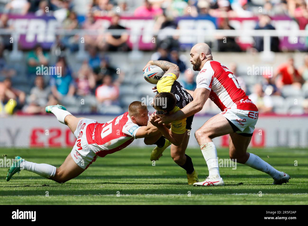 Salford Red Devils’ Deon Cross (centre) is tackled by Hull KR’s Mikey Lewis (left) and Hull KR’s Kane Linnett during the Betfred Super League match at St. James' Park, Newcastle upon Tyne. Picture date: Saturday June 3, 2023. Stock Photo