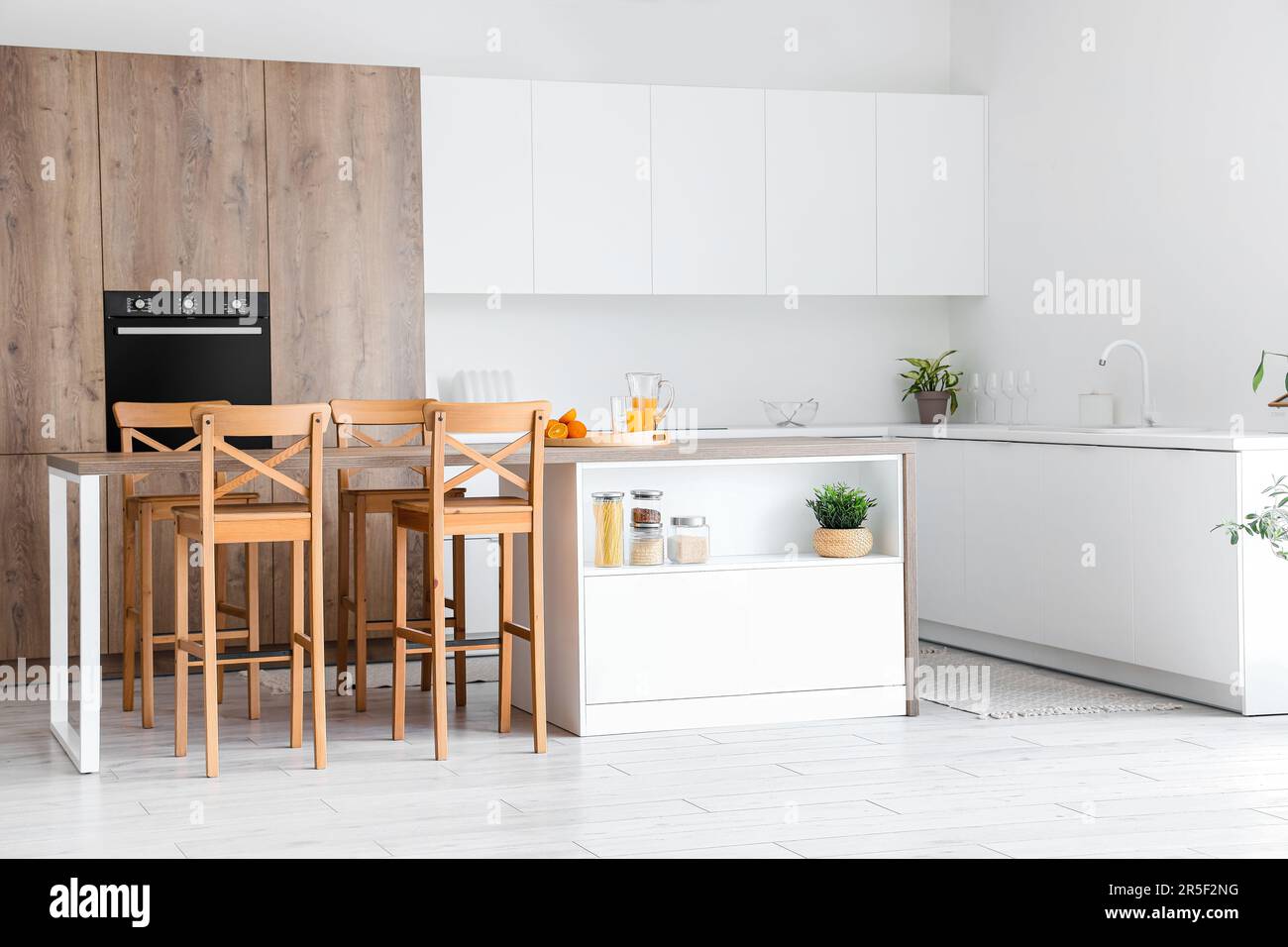 Interior of modern kitchen with island, chairs, built-in oven and white ...