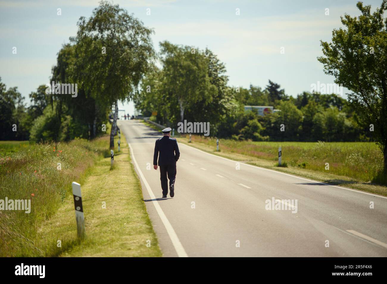 Eschede, Germany. 03rd June, 2023. A firefighter in uniform walks along a road at the memorial to the victims of the Eschede ICE accident. On June 03, 1998, after a wheel tire broke in Eschede, Lower Saxony, several rail cars of an ICE train crashed into a road bridge at a speed of 200. 101 people died. Credit: Gregor Fischer/dpa/Alamy Live News Stock Photo