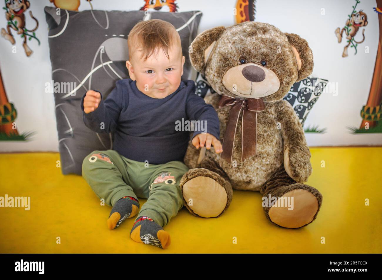 Portrait of a cute and smiling baby boy sitting with his beloved teddy ...