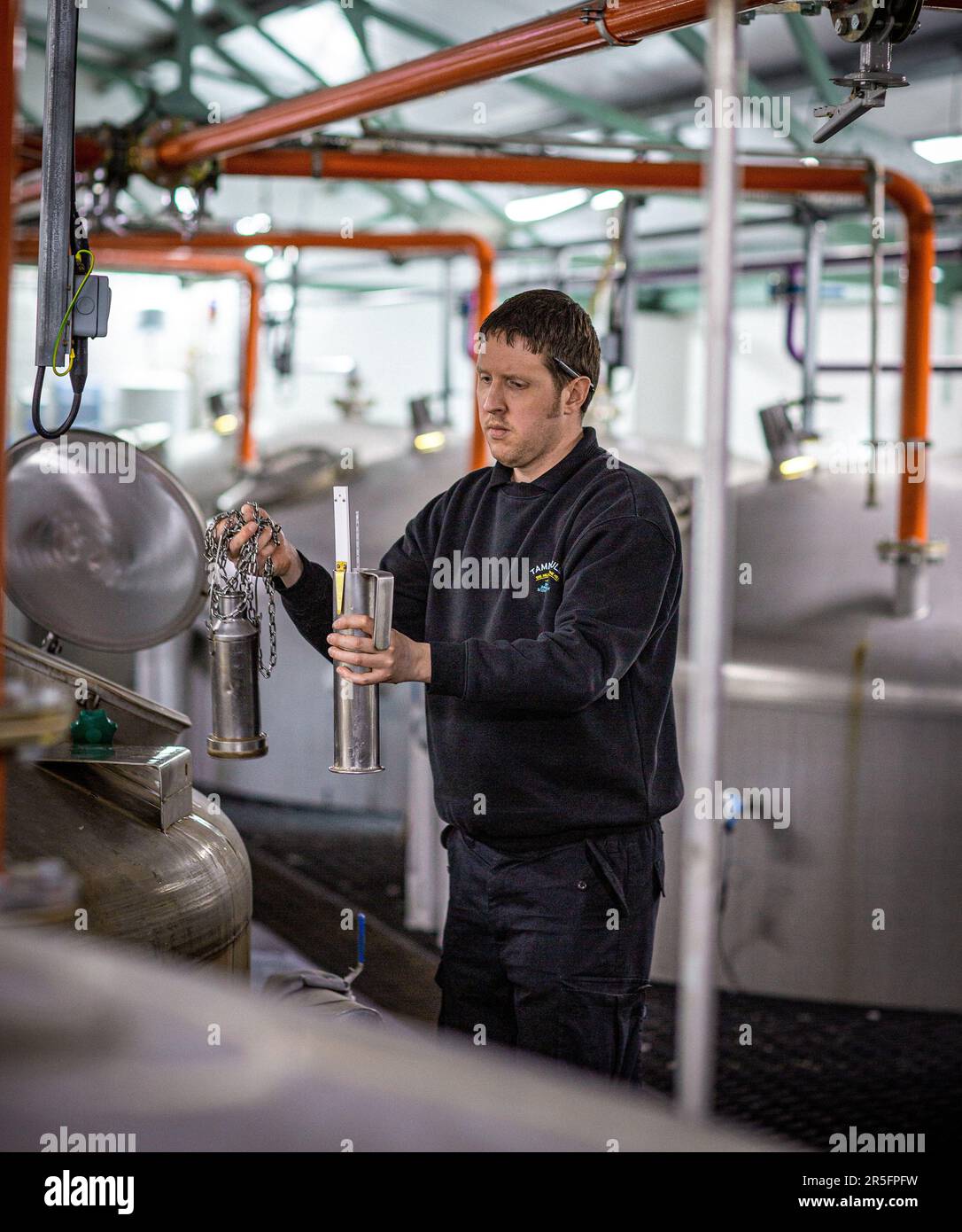 A distillery worker checking the process of fermentation at the Tamnavulin whisky distillery, Ballindalloch, Banffshire, Scotland, Stock Photo