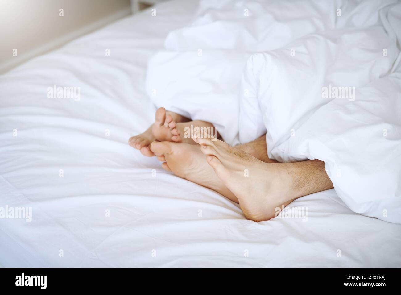 Its so cozy being in bed with you. a couples feet as they lay in bed