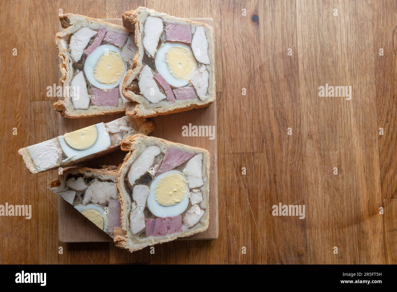 Tempting Chicken Ham and Egg Pie presented with nice slices on a small wooden board, ready to be enjoyed. Stock Photo