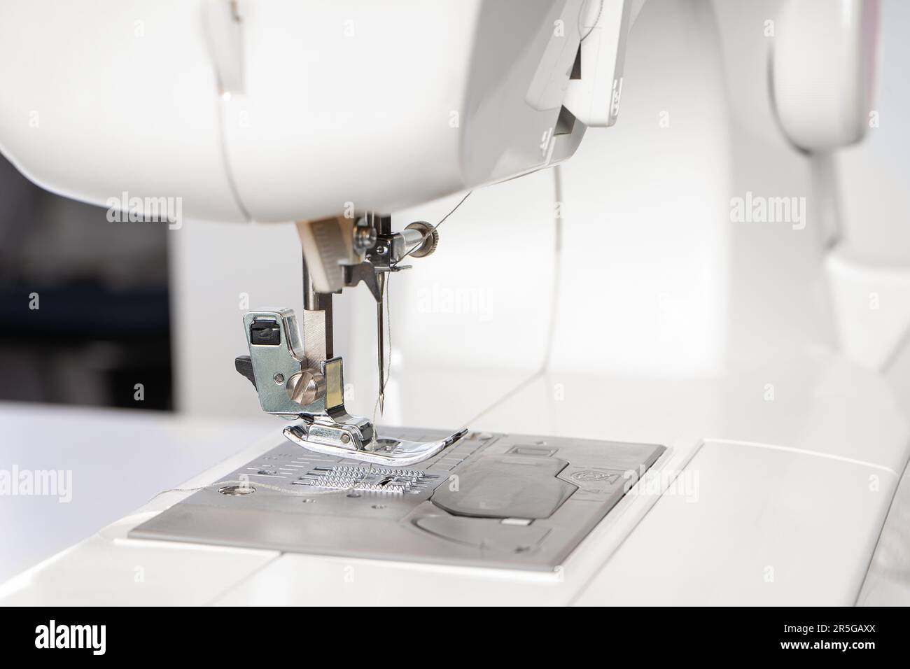 Modern white sewing machine presser foot closeup, macro. Sewing equipment, work tool for atelier