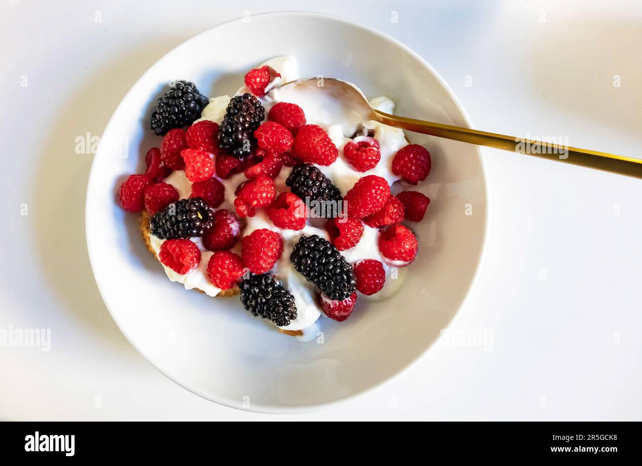 Raspberries and blackberries with yogurt in a white bowl Stock Photo