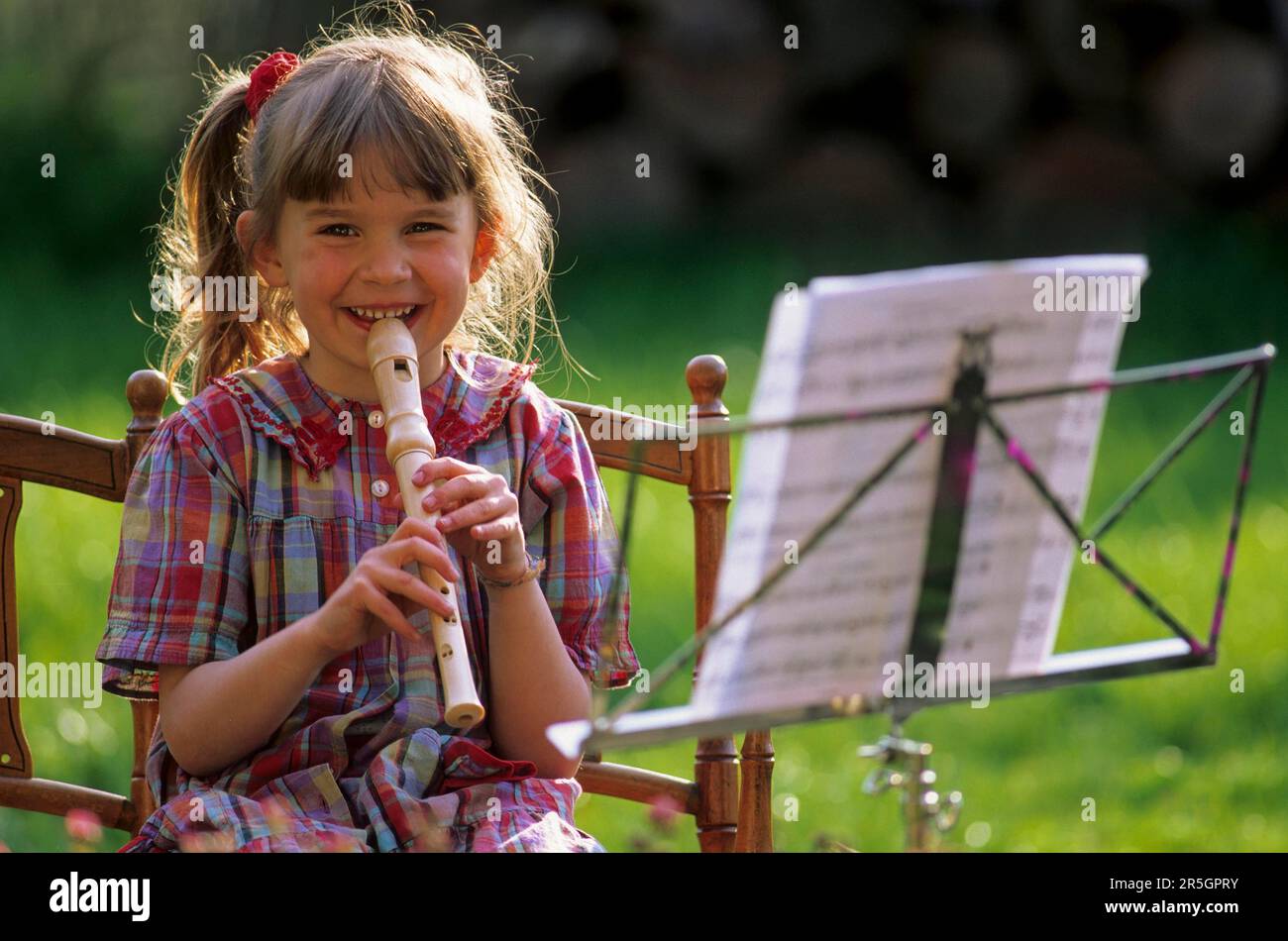 Little girl playing the flute from sheet music, music stand Stock Photo