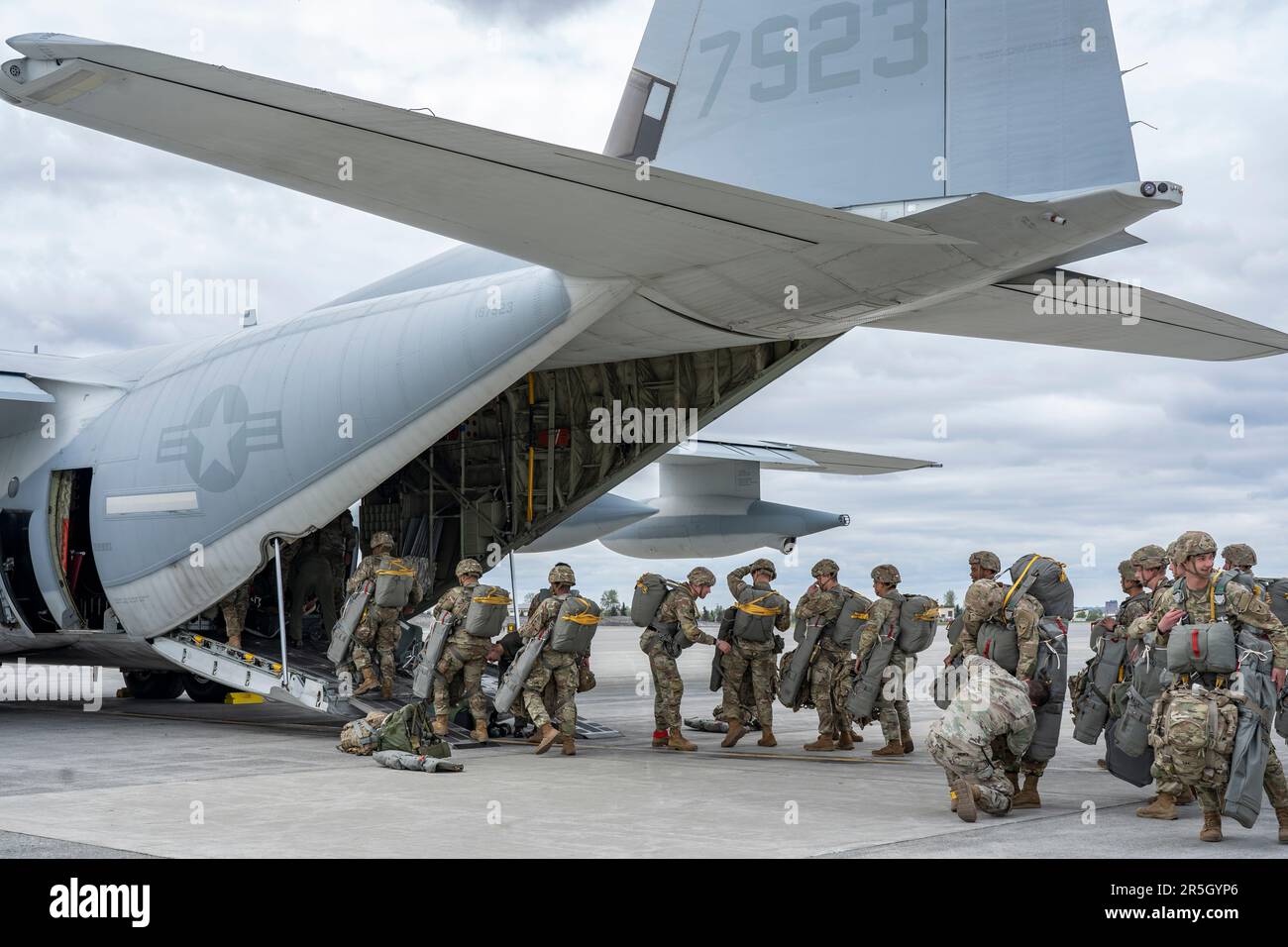 U.S. Army paratroopers assigned to the 3rd Battalion, 509th Parachute Infantry Regiment, 2nd Infantry Brigade Combat Team (Airborne), 11th Airborne Division, prepare to board a U.S. Marine Corps KC-130J aircraft assigned to the Marine Aerial Refueler Transport Squadron (VGMR) 153, Marine Corps Air Station Kaneohe Bay, Hawaii, at Joint Base Elmendorf-Richardson, Alaska, May 31, 2023. Paratroopers assigned to the 1st Battalion, 509th Infantry Regiment at Fort Polk, Louisiana, joined members from the 3-509th on their jump to celebrate the donation of items worn by World War II veteran Staff Sgt. Stock Photo