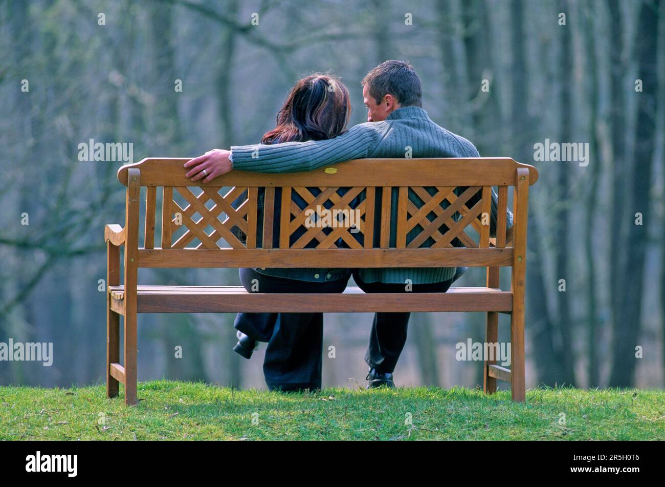 Couple sitting on park bench Stock Photo