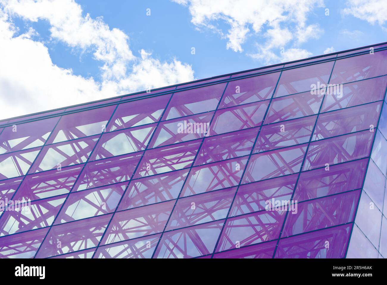 Stylish Glass Facade of Violet Tinted Semi-Transparent Glass Building Against Blue Sky with Sunbeams. Modern Architecture Concept Stock Photo