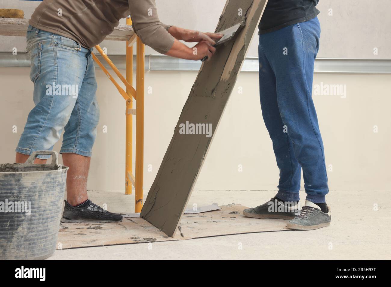Worker spreading adhesive mix over tile with spatula, closeup Stock Photo