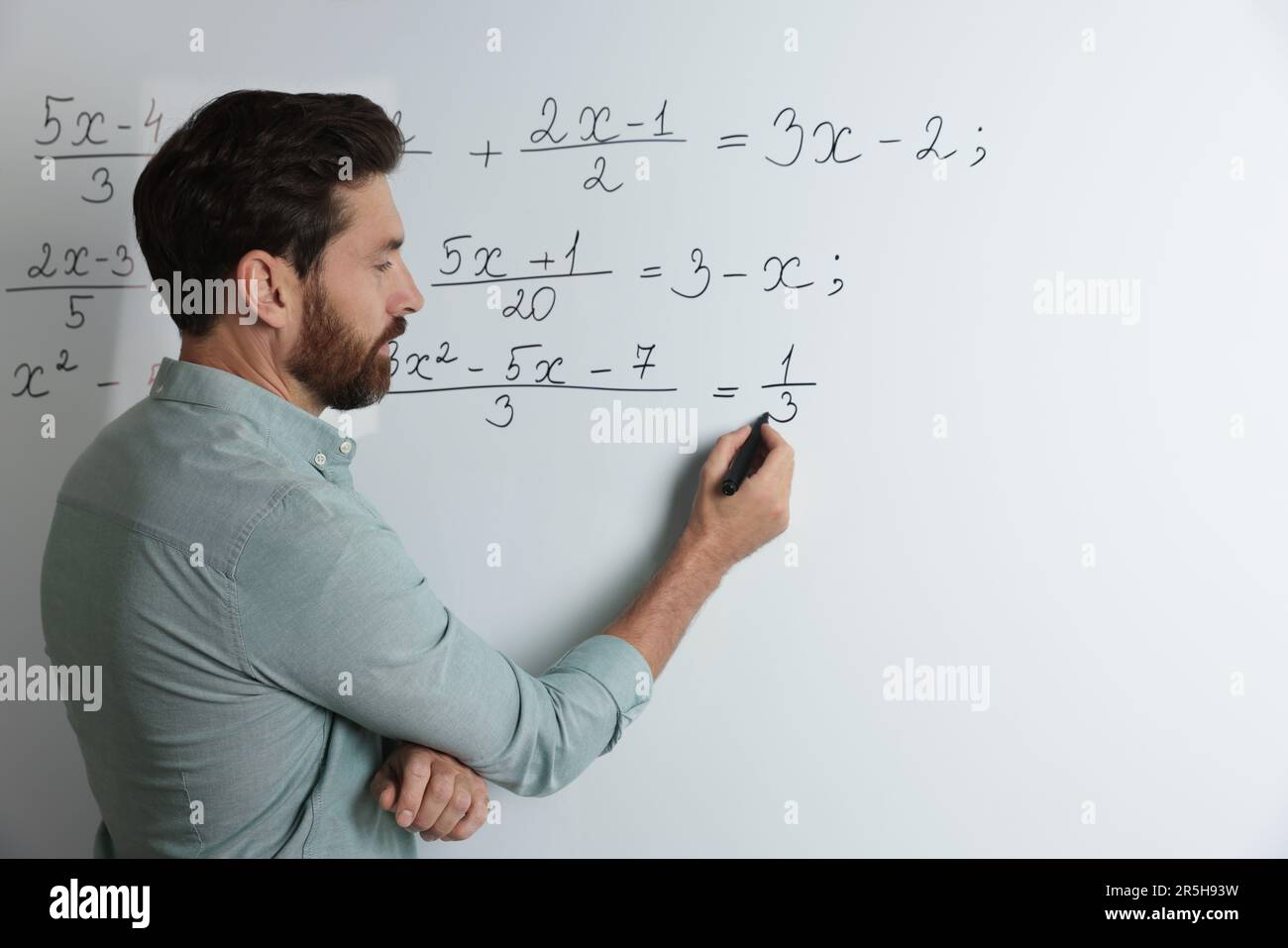 Mature teacher explaining mathematics at whiteboard in classroom Stock ...