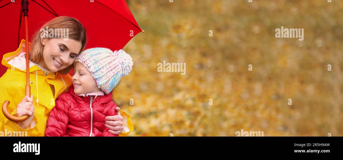 Mother and daughter with umbrella in autumn park on rainy day, space ...