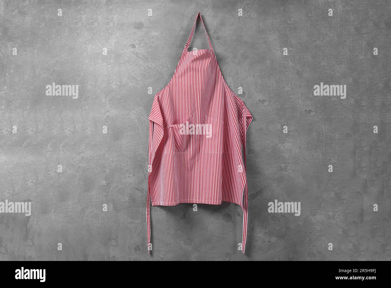 Clean red striped apron on grey tiled wall Stock Photo - Alamy