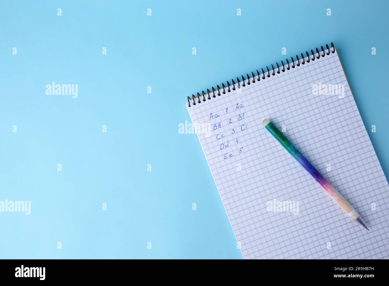Letters and numbers written in notepad with erasable pen on light blue ...