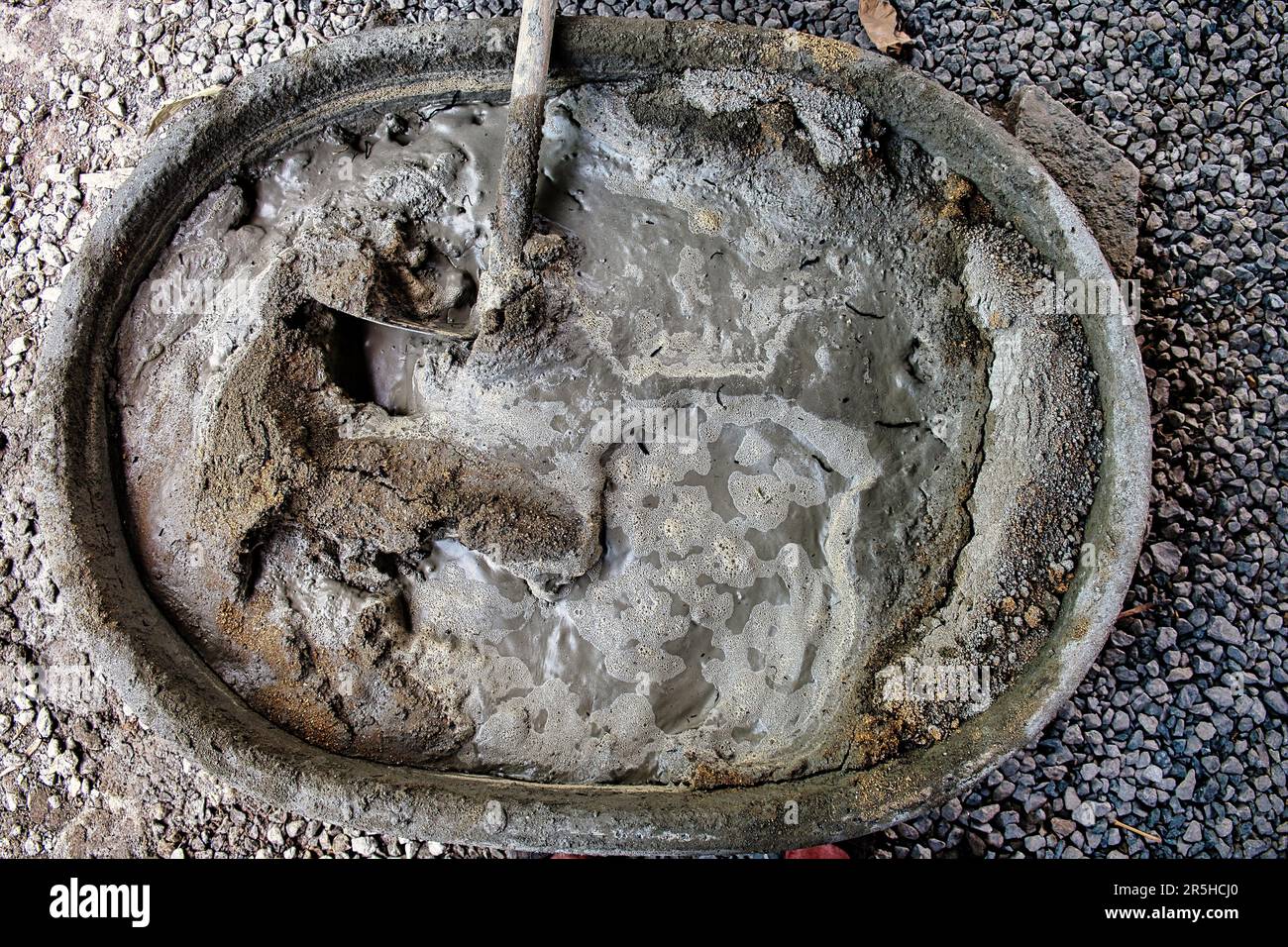 Mixing sand, cement, gravel and water in a tub to make concrete at a