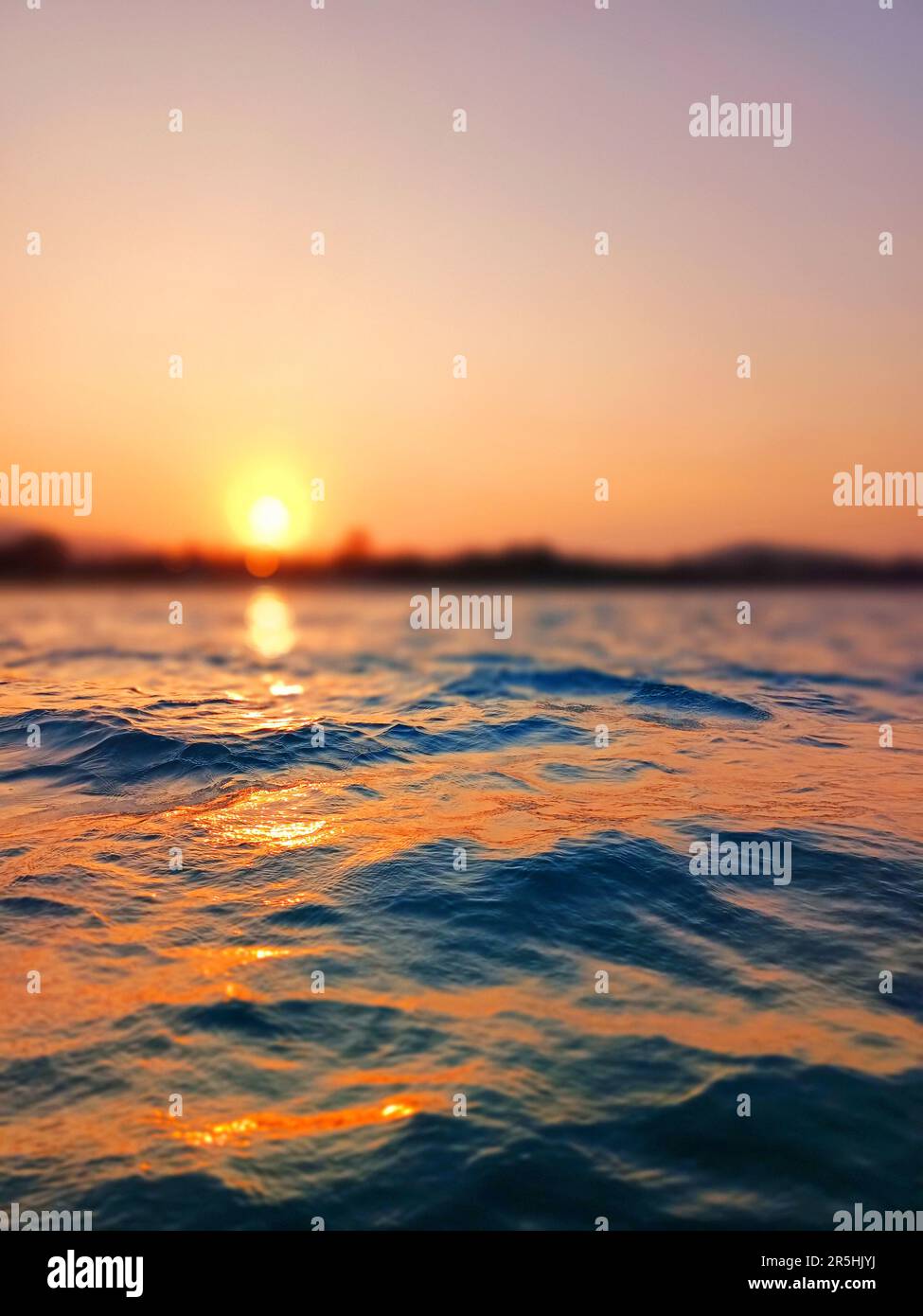 Sea wave splash, sunset blurred bokeh background, ocean water surf ripple texture, sunrise soft focus, tropical island beach dawn, sundown orange sun Stock Photo