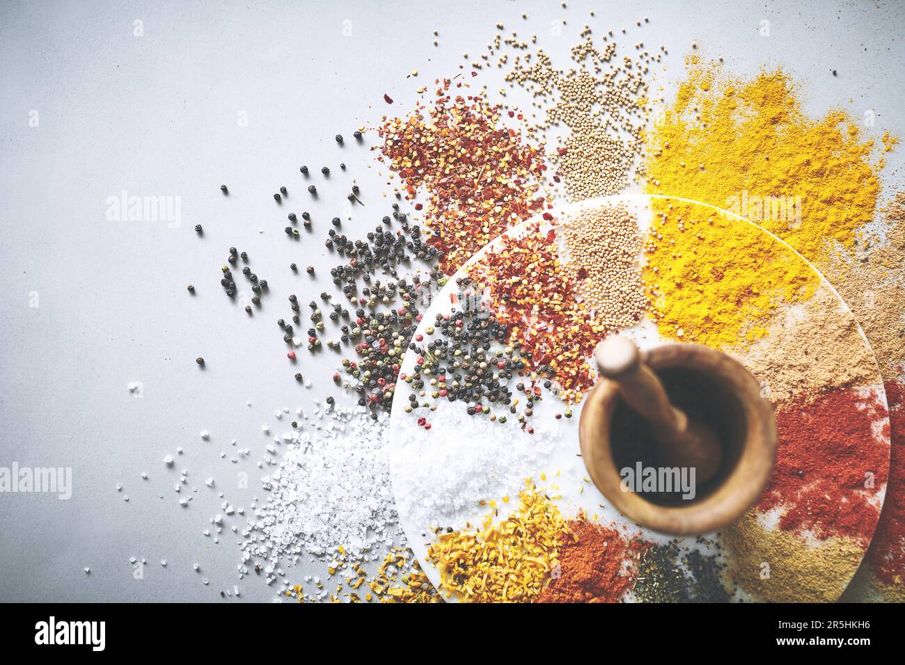 This combination will certainly earn you compliments when entertaining. a pestle and mortar with an assortment of spices scattered around it. Stock Photo