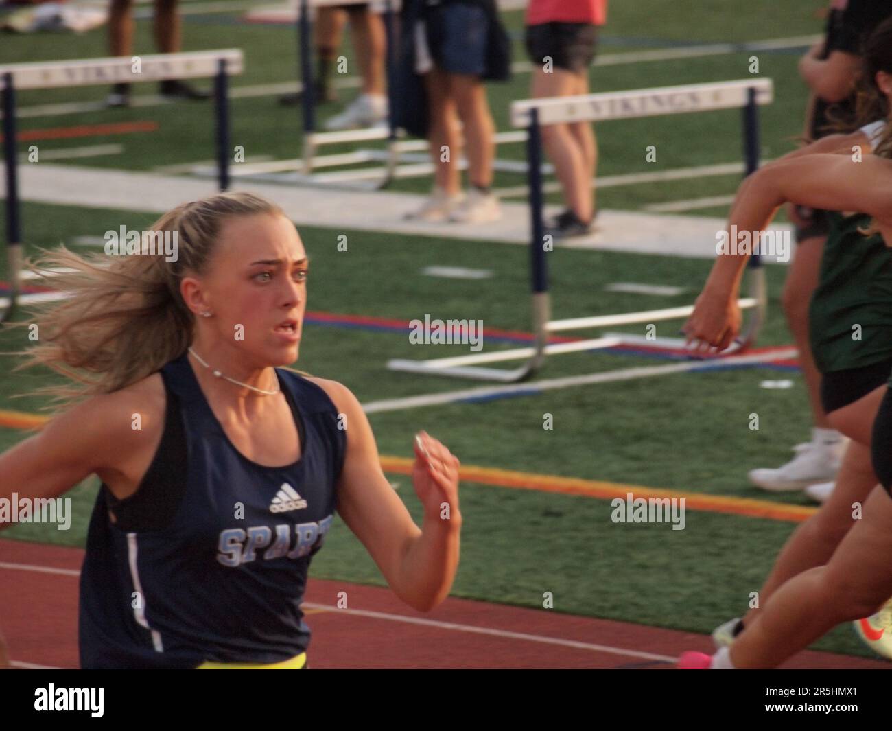 High school sprinters struggling to finish a 400 meter relay race. Determination and strength are shown on the faces of the competitors. Stock Photo