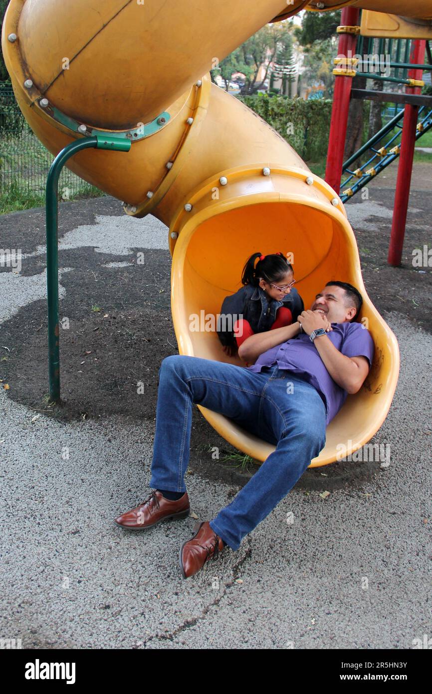 Divorced single dad and 4-year-old daughter Latino brunettes play on outdoor park playground spend quality time together tech-free Stock Photo