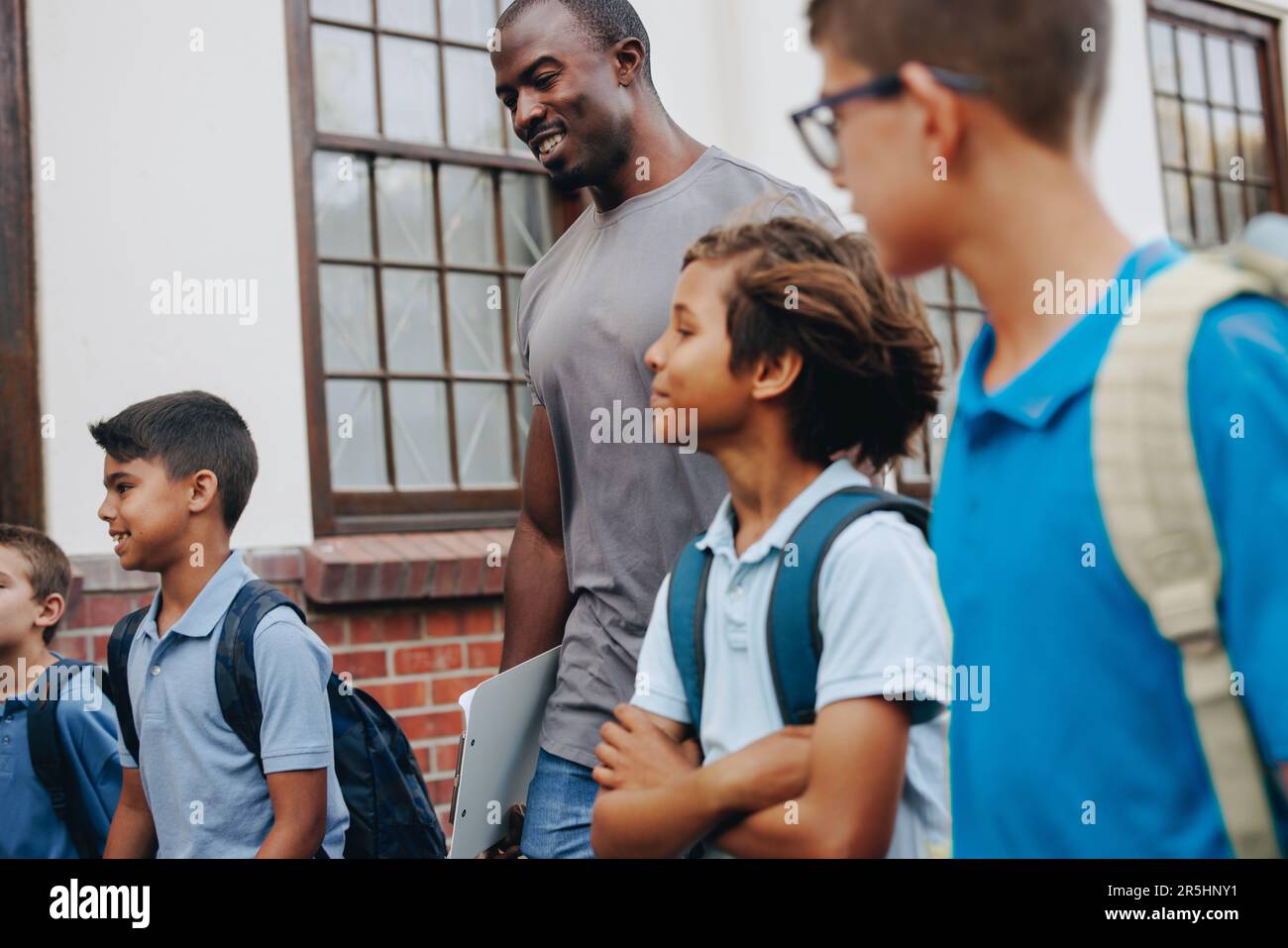 Male school teacher walking outside class with his students. Elementary school teacher taking a group of children to a lesson. education and child dev Stock Photo