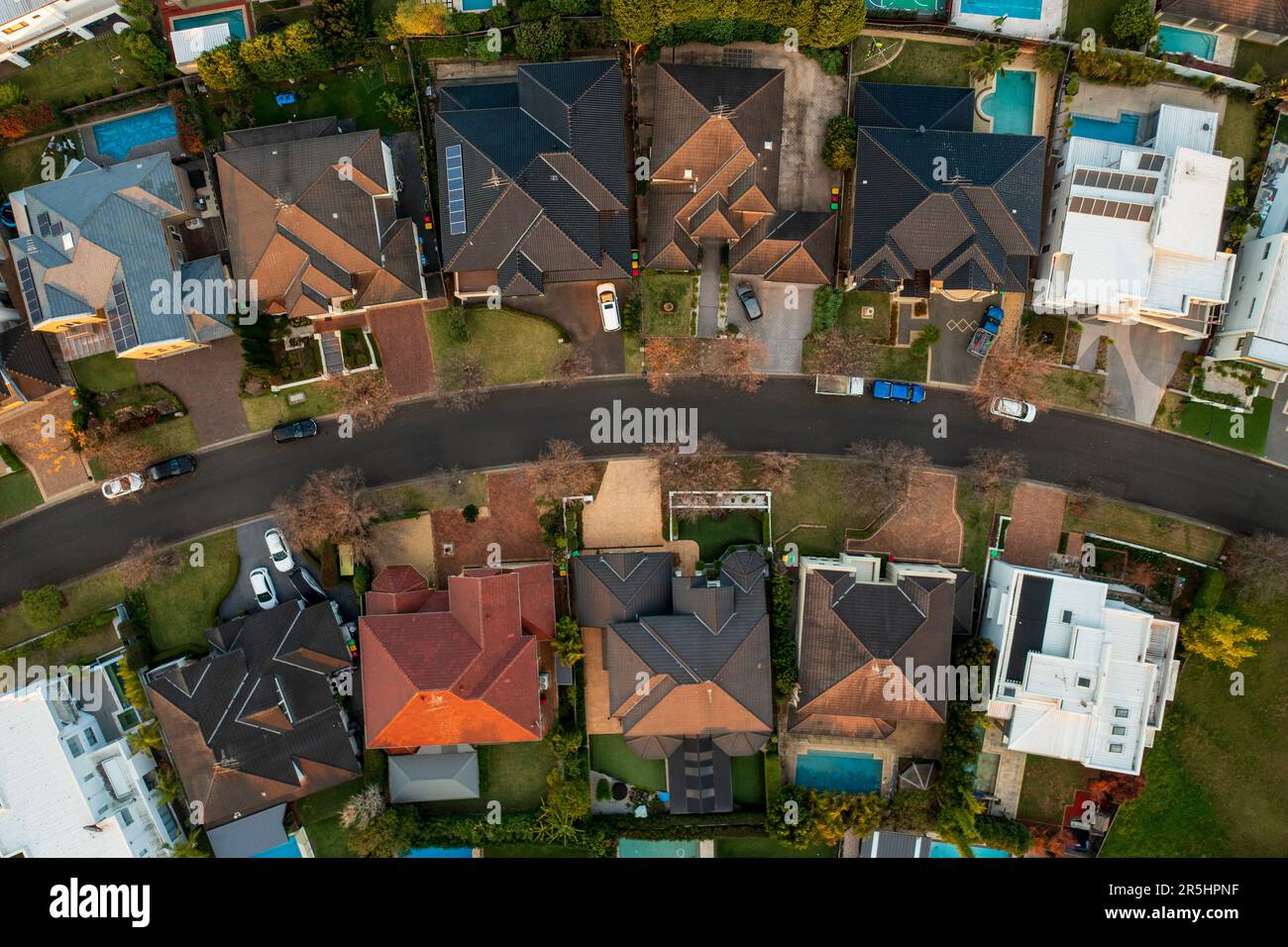 Aerial top down view of upmarket houses on a curved street in the fading winter sun in suburban Sydney, Australia. Stock Photo
