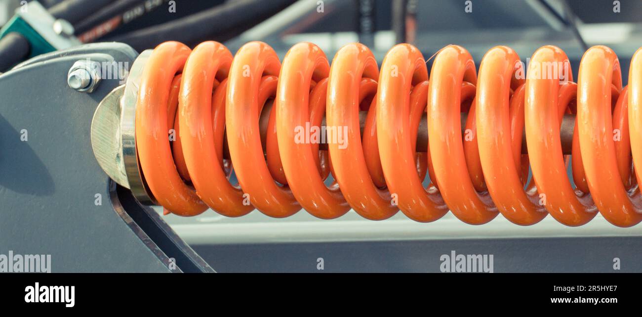 Big and hard orange steel spring as part and detail of industrial or ...