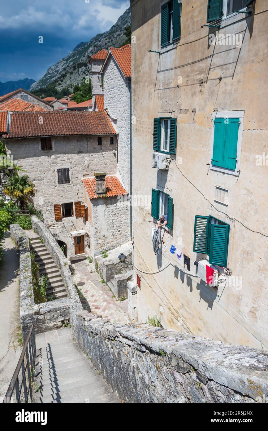 A woman leans out of her home to hang out her laundry in the old town of Kotor, Montenegro pictured in May 2023. Stock Photo