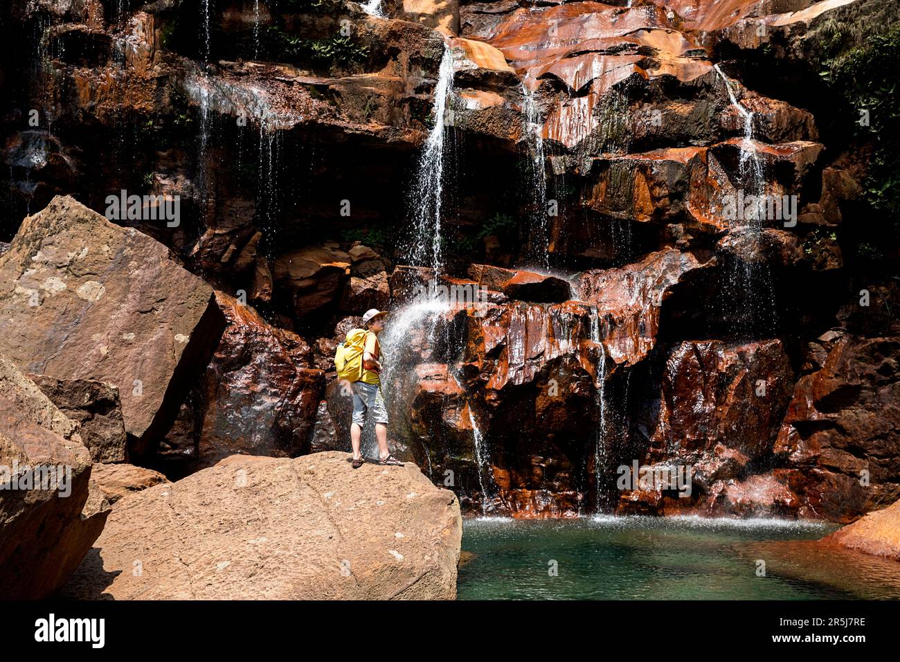 Tourist hiker looking at the spectacular Prut waterfall with turquoise natural swimming pool in Cherrapunji region in Meghalaya, India Stock Photo