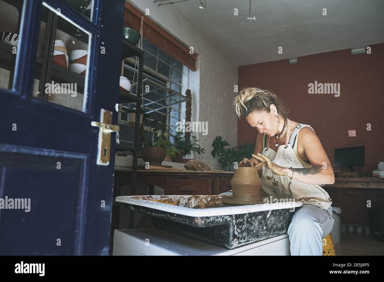 A beautiful mind makes beautiful things. a young woman working with clay in a pottery studio. Stock Photo