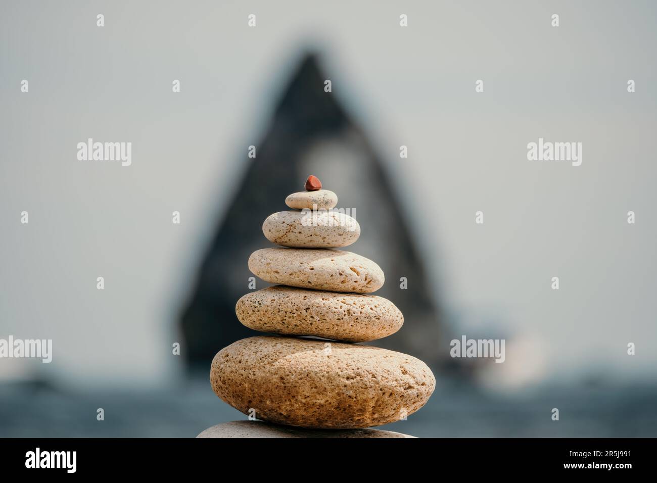 balanced rock pyramid stands tall on sea pebble beach. Selective focus ...