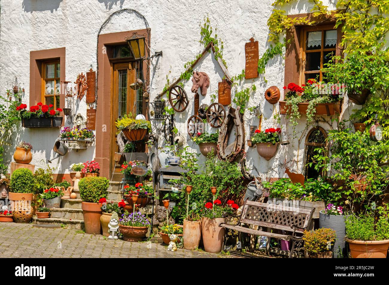 Schalkenmehren, Germany, May 26, 2023: white plaster facade with pots, plants, wheels and other traditional objects Stock Photo