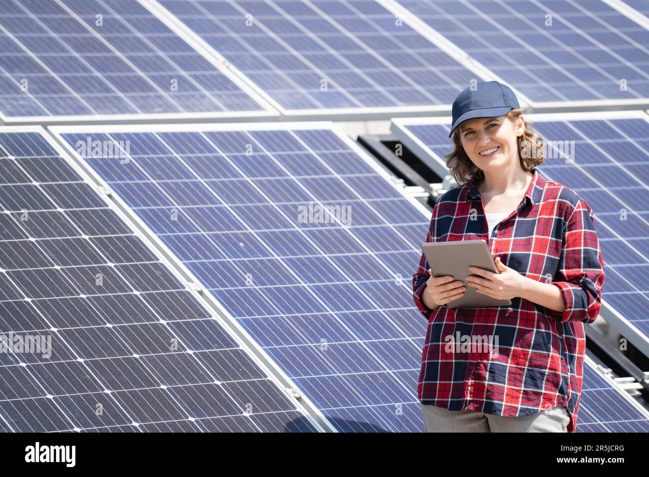 Woman with digital tablet on a background of mobile solar power station. Stock Photo