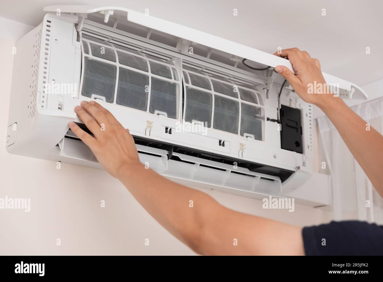 Electrician repairing air conditioner indoors. Man cleaning air