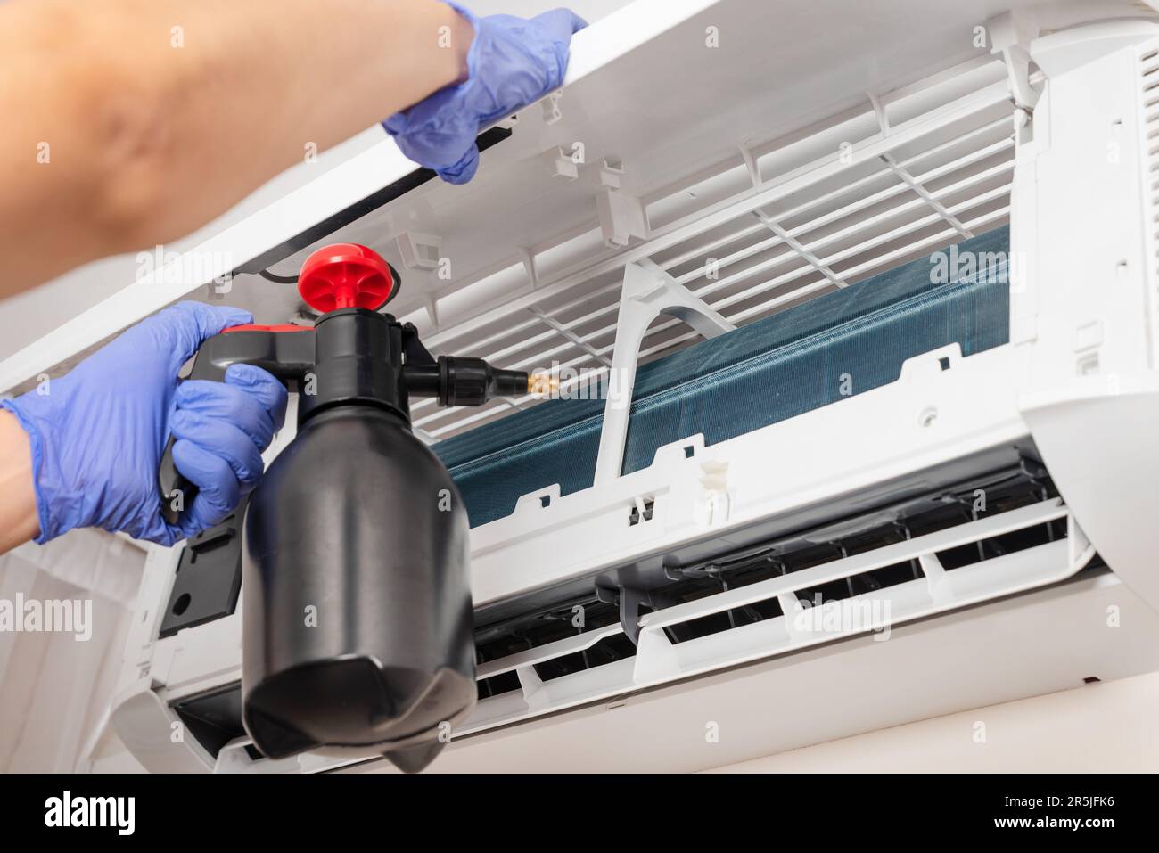 Electrician repairing air conditioner indoors. Man cleaning air