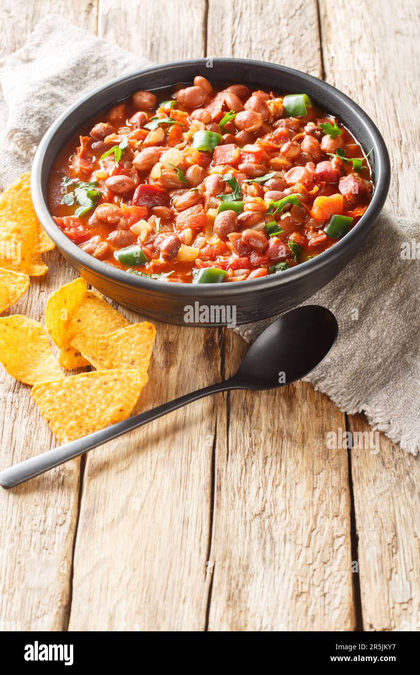 Frijoles charros or charros beans mexican traditional food with chorizo bacon and onions spicy food closeup on the bowl on the table. Vertical Stock Photo