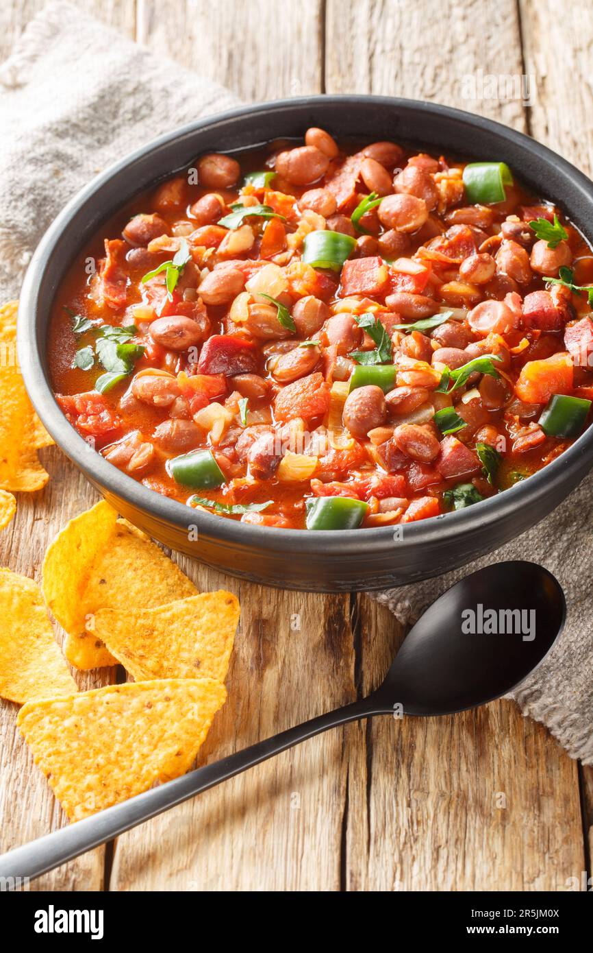 Mexican Charro Beans or Frijoles Charros with bacon, tomato, onions, ham, and jalapenos closeup on the bowl on the table. Vertical Stock Photo