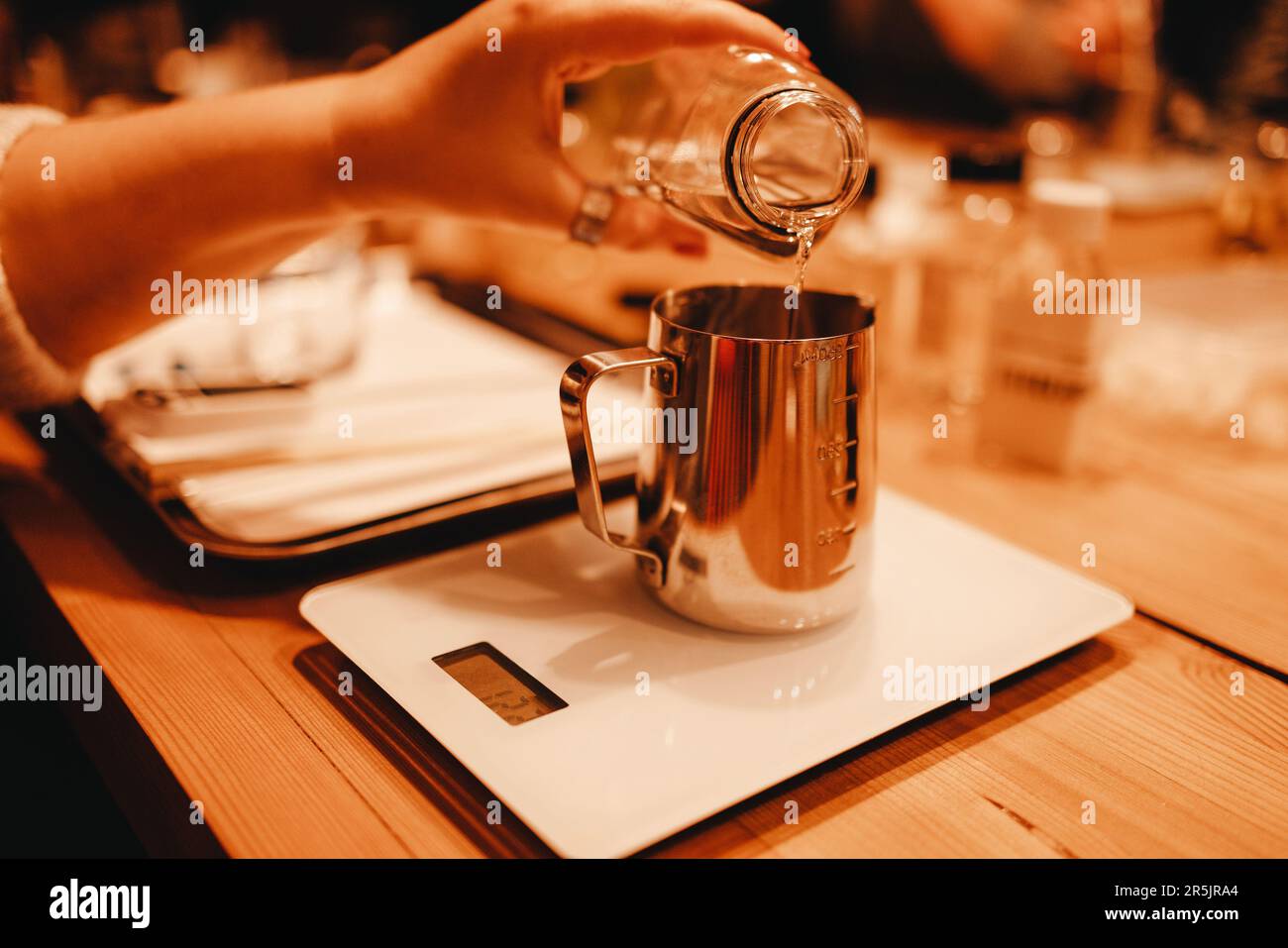 Pouring melted wax into glass. Set for crafting candle on metal tray