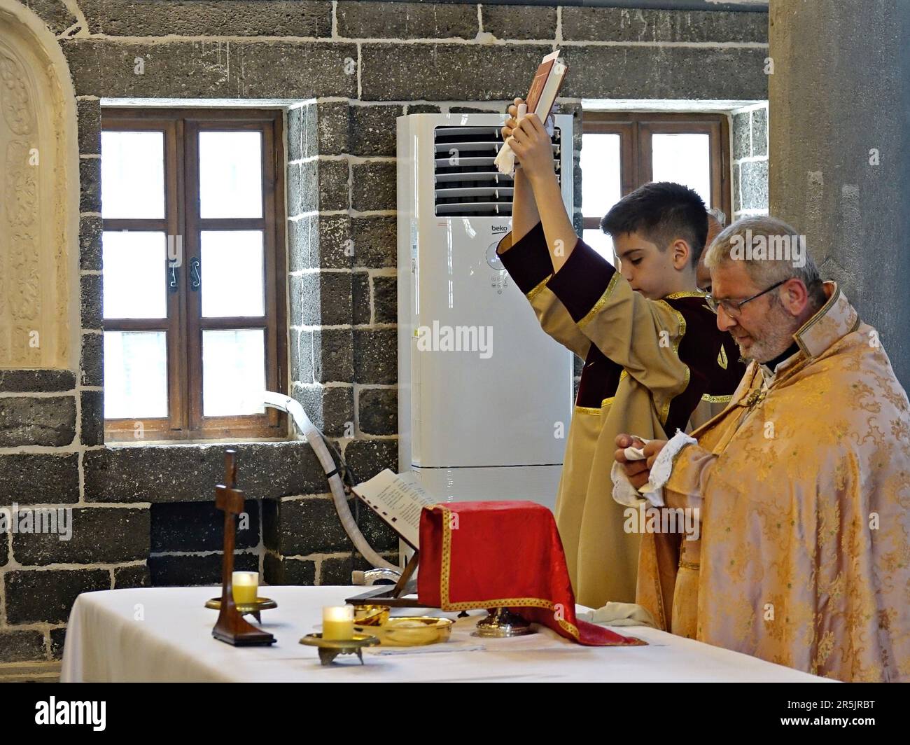 A young man holds up a holy book, the Bible during the ritual at Diyarbak?r Surp Hovsep Church. At the Surp Hovsep Armenian Catholic Church, which was heavily damaged in clashes between armed Kurdish PKK militants and Turkish security forces in the center of Diyarbakir in 2015 and repaired as a result of a 4-year restoration, the second ritual in the last 100 years after the first ritual in 2021. Very few Armenians who came from Istanbul and lived in Diyarbakir attended the ceremony. The ritual was led by Senior Priest Abraham Firat and Subordinate Deacon Jan Acemoglu, who were ordained from I Stock Photo