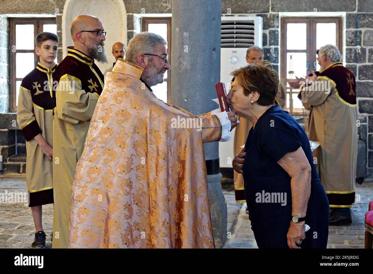 A woman kisses a Bible in the hands of Senior Priest Abraham Firat after the ritual at Diyarbak?r Surp Hovsep Church. At the Surp Hovsep Armenian Catholic Church, which was heavily damaged in clashes between armed Kurdish PKK militants and Turkish security forces in the center of Diyarbakir in 2015 and repaired as a result of a 4-year restoration, the second ritual in the last 100 years after the first ritual in 2021. Very few Armenians who came from Istanbul and lived in Diyarbakir attended the ceremony. The ritual was led by Senior Priest Abraham Firat and Subordinate Deacon Jan Acemoglu, wh Stock Photo