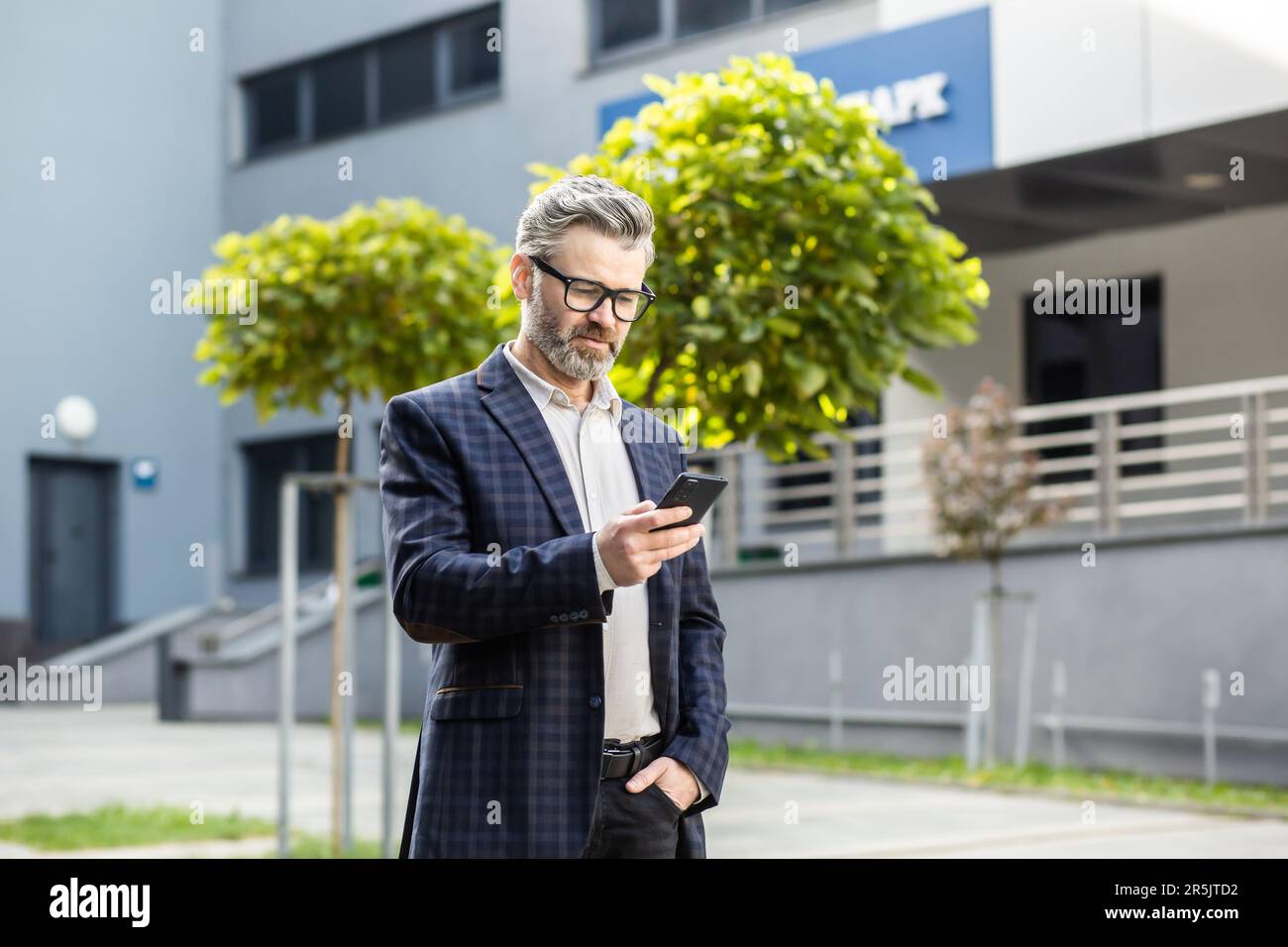 Serious thinking and focused mature businessman using app on phone ...