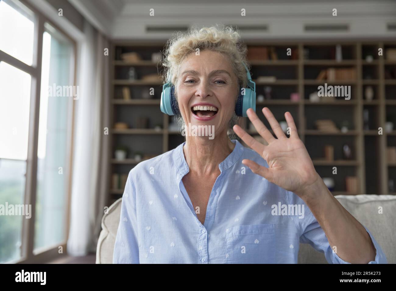 Happy mature woman in wireless headphones smiling at camera Stock Photo ...
