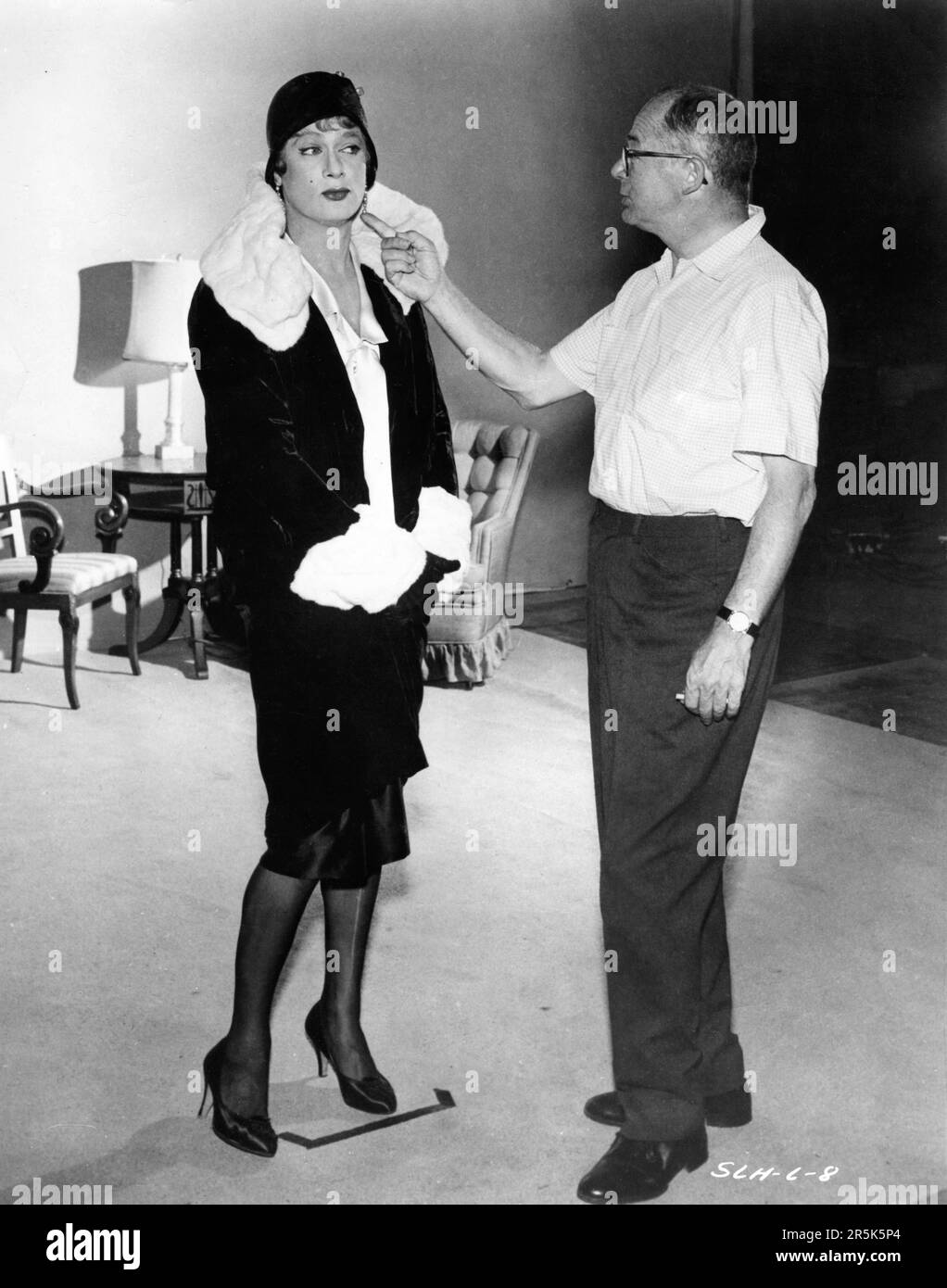 TONY CURTIS has his female costume checked by Director BILLY WILDER on set candid during filming of SOME LIKE IT HOT 1959 director BILLY WILDER screenplay Billy Wilder and I.A.L. Diamond Ashton Productions / The Mirisch Corporation / United Artists Stock Photo