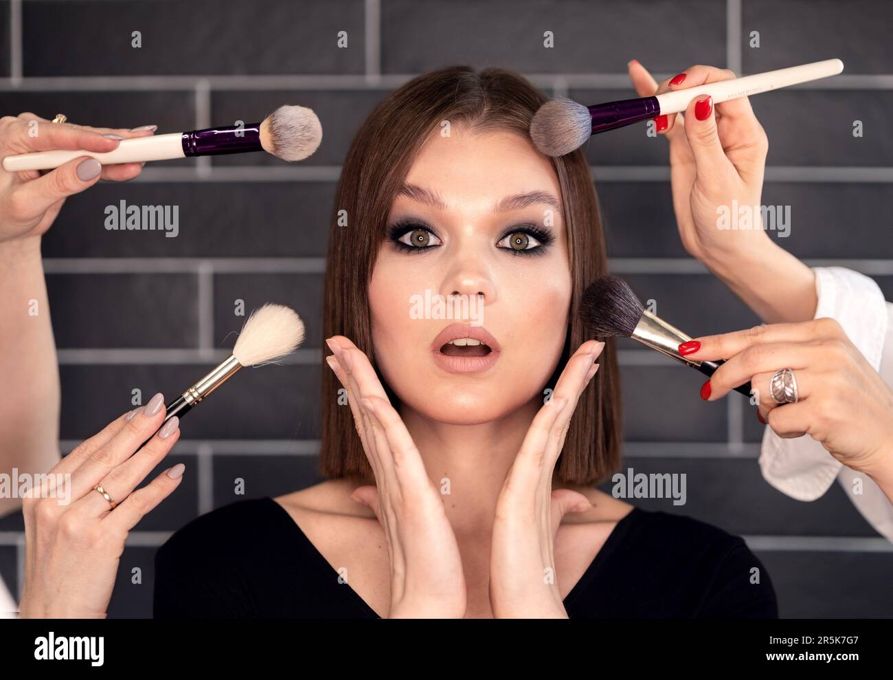 makeup artists do makeup in four hands model surprised Stock Photo Alamy