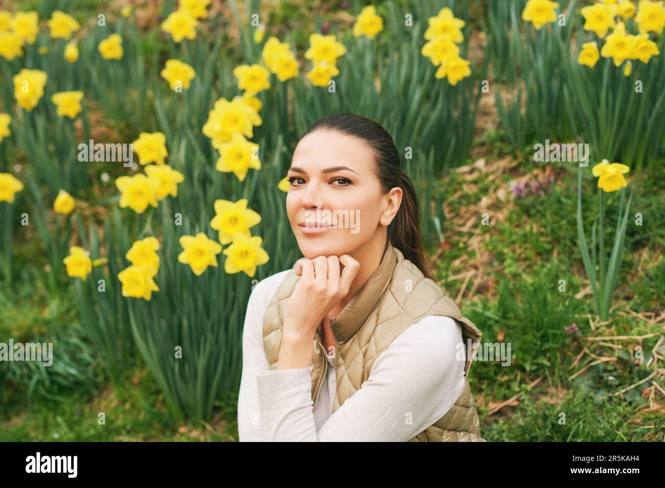 Spring portrait of young beautiful woman sitting in a field of blooming daffodils Stock Photo