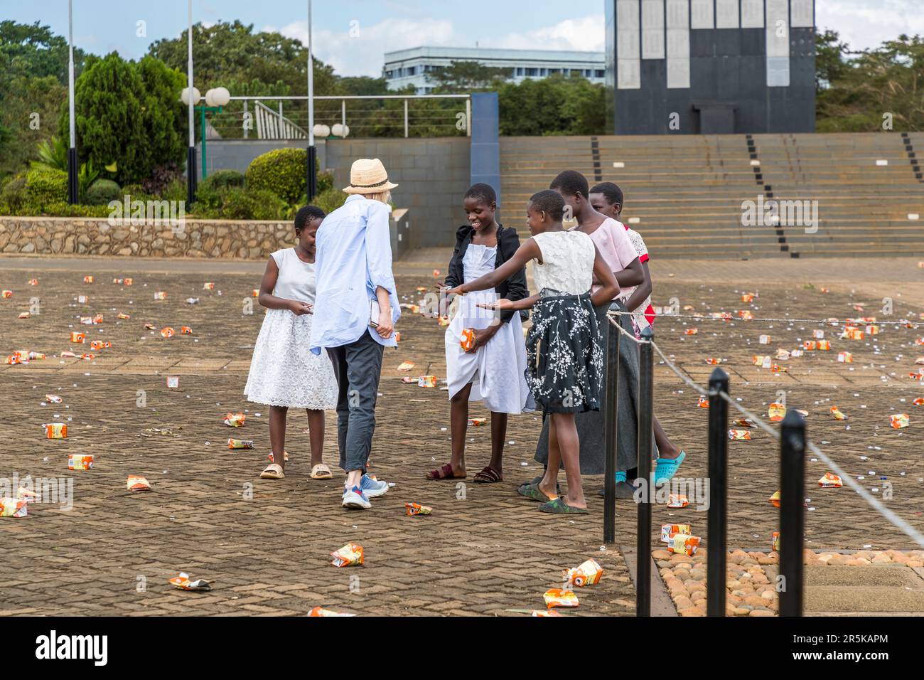 Girls collect plastic rings from tetra packs to make jewelry after a rally in front of the Memorial War Tower in Lilongwe. Young girls collect the cap rings of the maheu packs discarded on the national holiday in honor of Malawi's first president (Hastings Kamuzu Banda) to make jewelry. Maheu or Mahewu is a typical drink in Malawi made from fermented maize. Lilongwe, Malawi Stock Photo