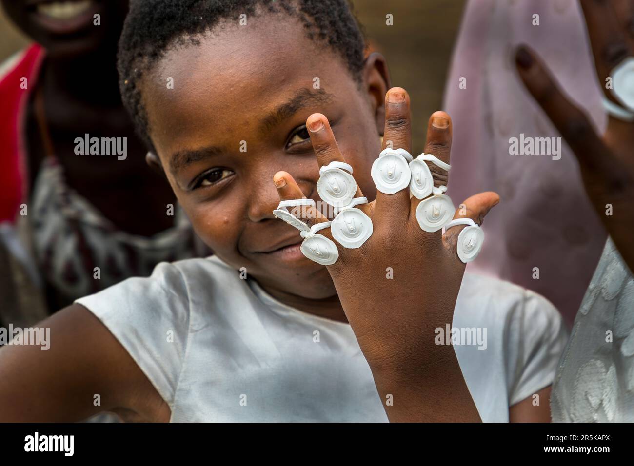 Young girls collect the cap rings of the maheu packs discarded on the national holiday in honor of Malawi's first president (Hastings Kamuzu Banda) to make jewelry. Maheu or Mahewu is a typical drink in Malawi made from fermented maize. Lilongwe, Malawi Stock Photo