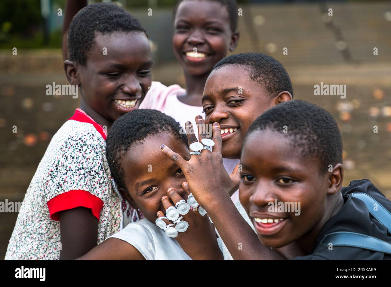 Young girls collect the cap rings of the maheu packs discarded on the national holiday in honor of Malawi's first president (Hastings Kamuzu Banda) to make jewelry. Maheu or Mahewu is a typical drink in Malawi made from fermented maize. Lilongwe, Malawi Stock Photo