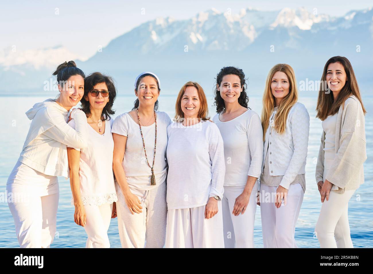 Group portrait of beautiful women posing outside with beautiful mountain landscape on background, wearing white clothes Stock Photo