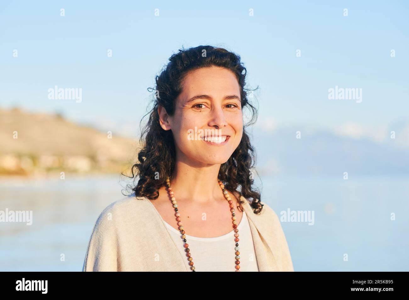 Outdoor portrait of beautiful middle age hispanic woman enjoying nice sunny day by the mountain lake Stock Photo